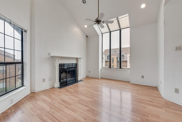 unfurnished living room with light wood finished floors, a ceiling fan, a tile fireplace, high vaulted ceiling, and recessed lighting