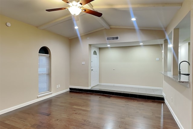 unfurnished room with baseboards, visible vents, a ceiling fan, dark wood-style floors, and vaulted ceiling with beams