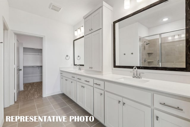 full bathroom with a sink, a stall shower, a walk in closet, and tile patterned floors