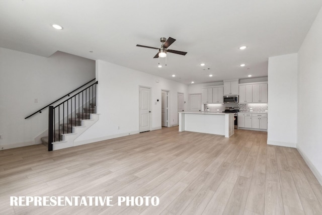 unfurnished living room featuring light wood-style floors, recessed lighting, stairway, and a ceiling fan