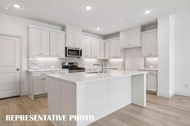 kitchen featuring appliances with stainless steel finishes, light countertops, a sink, and white cabinetry