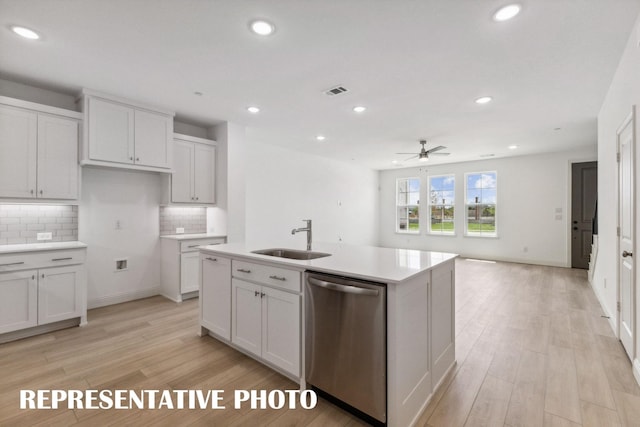 kitchen featuring dishwasher, light countertops, a sink, and white cabinetry