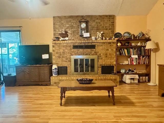 23319 Penninsula Pt, Frankston, TX 75763 - living room featuring wood finished floors, vaulted ceiling, a ceiling fan, and a brick fireplace