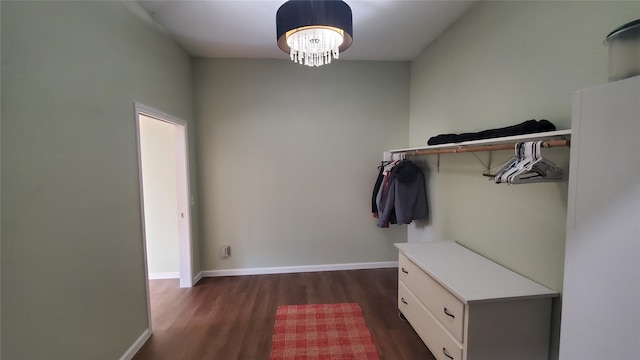 walk in closet with dark wood-style flooring and a chandelier
