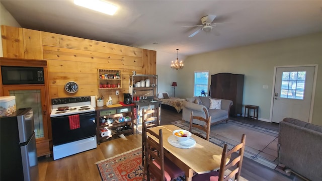 dining area featuring ceiling fan with notable chandelier and wood finished floors