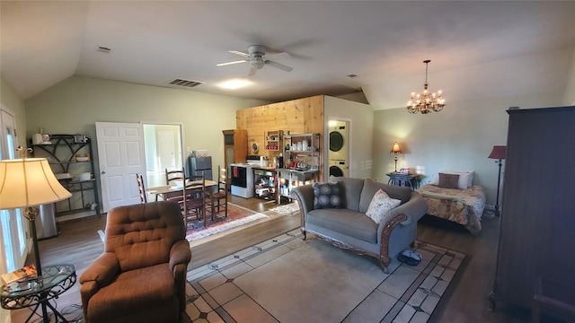 living area with stacked washing maching and dryer, vaulted ceiling, ceiling fan with notable chandelier, and visible vents