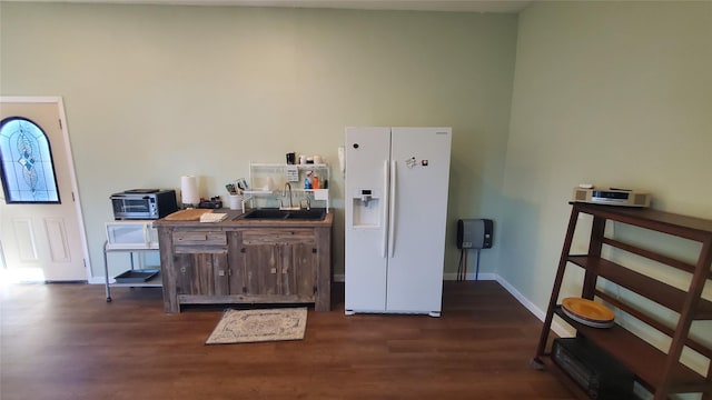 kitchen featuring baseboards, a sink, dark wood-style floors, and white appliances
