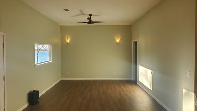 empty room with dark wood-style floors, a ceiling fan, visible vents, and baseboards