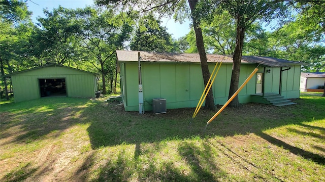 back of house featuring a lawn, board and batten siding, a detached garage, and entry steps