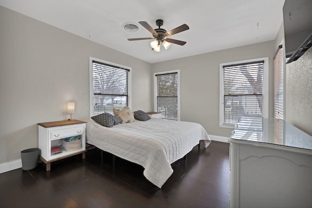 bedroom featuring visible vents, multiple windows, baseboards, and dark wood-type flooring