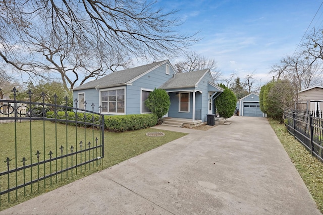 bungalow-style home featuring a fenced front yard, concrete driveway, a garage, an outdoor structure, and a front lawn