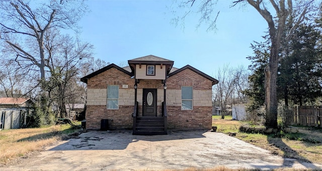 view of front of property with brick siding, a patio, and fence