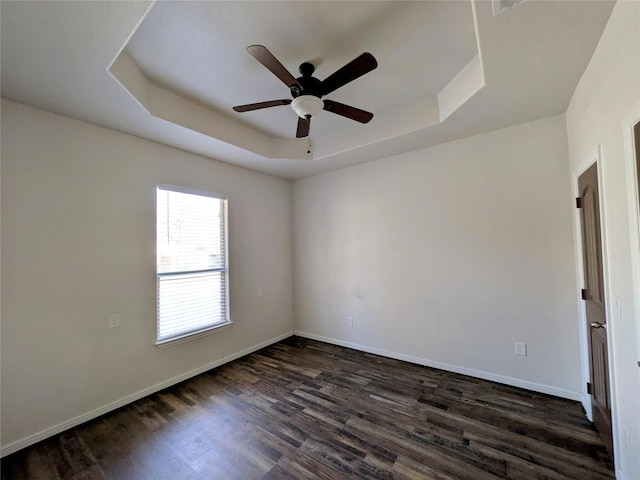 unfurnished room featuring dark wood-style floors, baseboards, a tray ceiling, and a ceiling fan