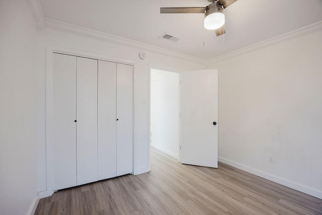 unfurnished bedroom featuring light wood finished floors, baseboards, visible vents, ornamental molding, and a closet