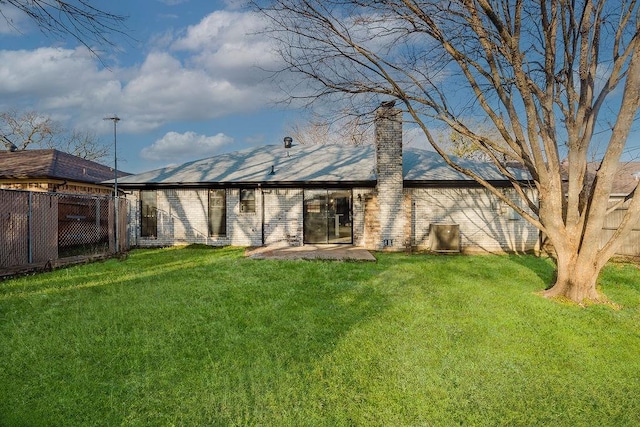 rear view of property with a patio area, a chimney, fence, and a yard