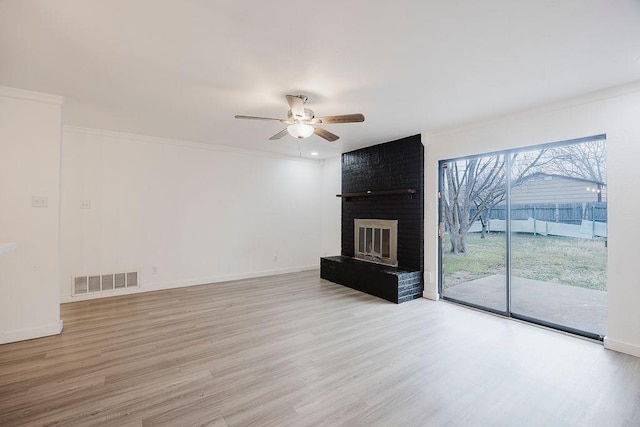 unfurnished living room featuring light wood-type flooring, a brick fireplace, visible vents, and ceiling fan