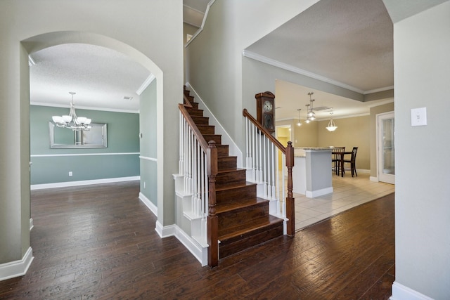 staircase with baseboards, a textured ceiling, ornamental molding, and wood finished floors