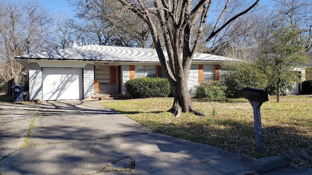 single story home featuring a garage, a front yard, brick siding, and driveway