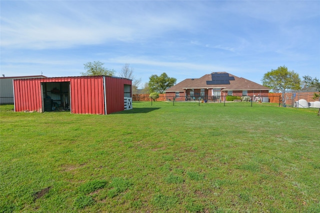 view of yard featuring fence, an outdoor structure, and an outbuilding