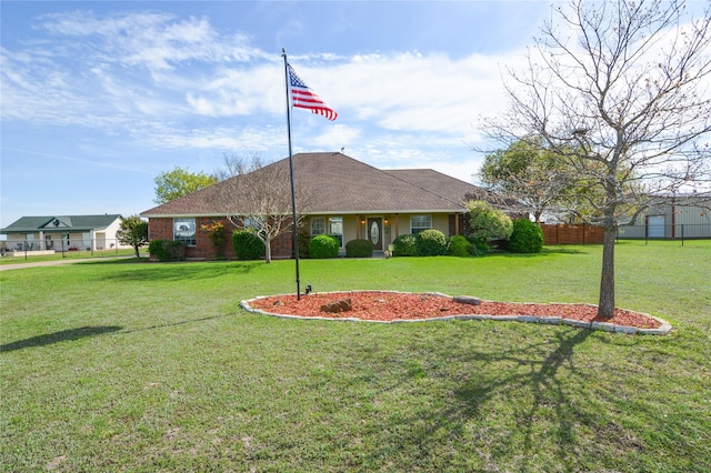 view of front of home with brick siding, fence, and a front yard