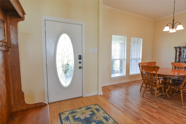 entrance foyer featuring a notable chandelier, light wood-type flooring, baseboards, and crown molding