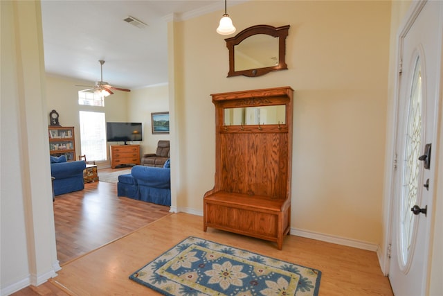 entryway featuring baseboards, visible vents, wood finished floors, and ornamental molding