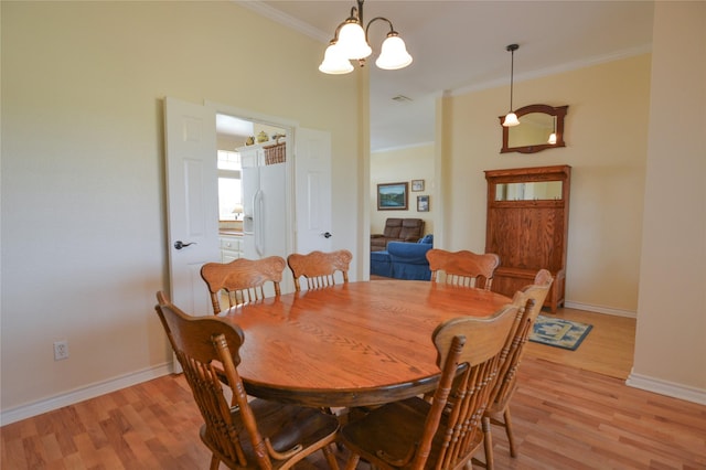 dining room with baseboards, light wood finished floors, an inviting chandelier, and crown molding