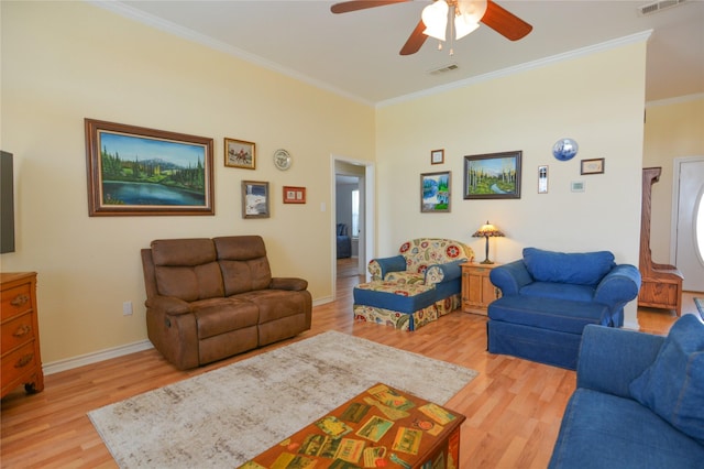 living area with visible vents, baseboards, a ceiling fan, light wood-style flooring, and crown molding