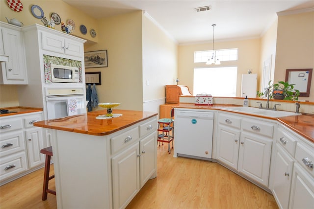 kitchen with white appliances, visible vents, butcher block counters, white cabinetry, and a sink