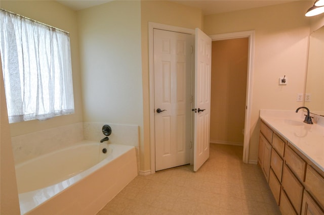 full bathroom with a garden tub, vanity, baseboards, and tile patterned floors