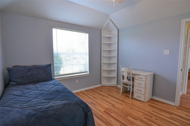 bedroom with light wood finished floors, baseboards, and vaulted ceiling