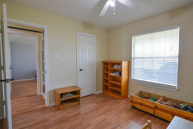 interior space featuring light wood-style floors, baseboards, and a ceiling fan