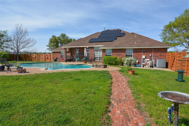 rear view of property featuring brick siding, a yard, a patio, solar panels, and a fenced backyard