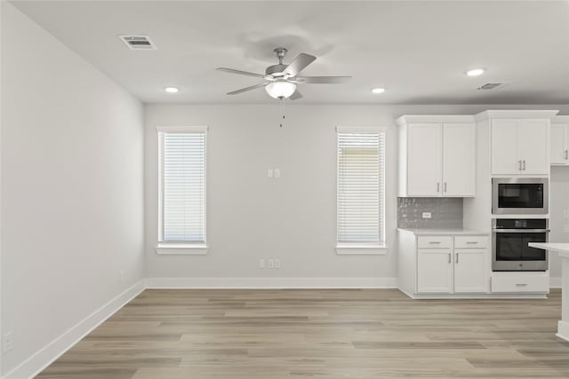 kitchen featuring oven, built in microwave, visible vents, light countertops, and decorative backsplash