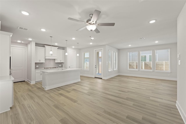 kitchen with light countertops, backsplash, a sink, and visible vents