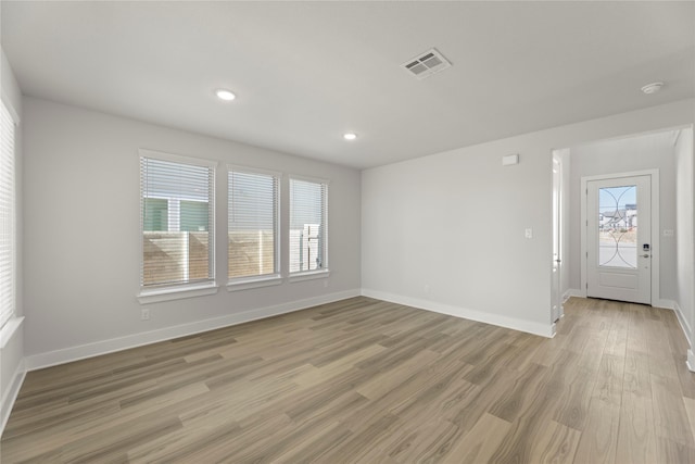 empty room with light wood-style flooring, visible vents, baseboards, and recessed lighting