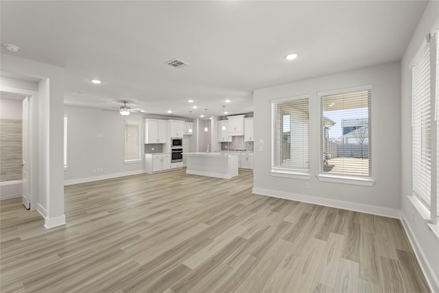 unfurnished living room with baseboards, visible vents, and recessed lighting