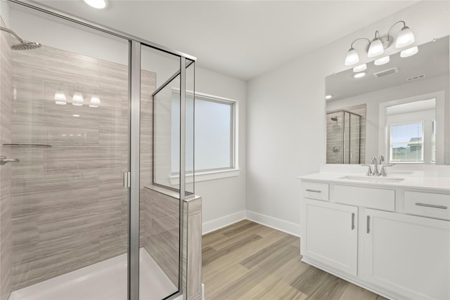 bathroom with visible vents, a stall shower, vanity, wood finished floors, and baseboards