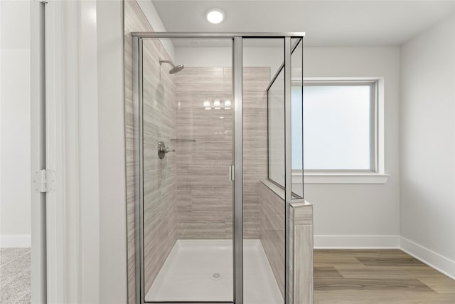 bathroom featuring wood finished floors, a shower stall, and baseboards