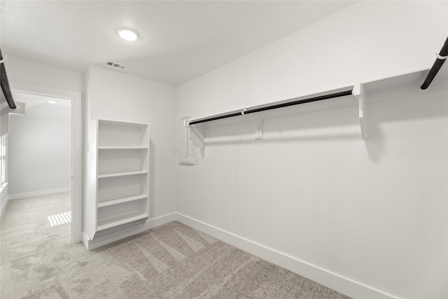 walk in closet with visible vents and light colored carpet