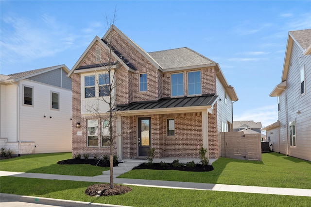 view of front of property featuring a front yard, a standing seam roof, and brick siding