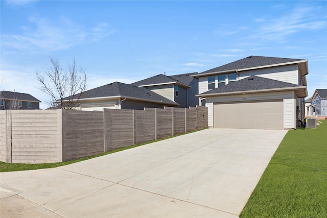 view of front of property with an attached garage, central air condition unit, fence, driveway, and a front lawn