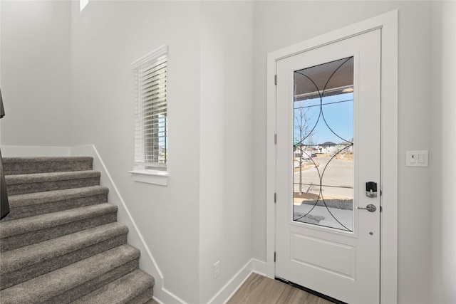 foyer with light wood-type flooring, plenty of natural light, stairway, and baseboards