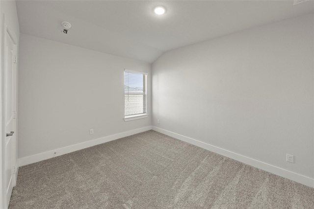 carpeted spare room with lofted ceiling and baseboards