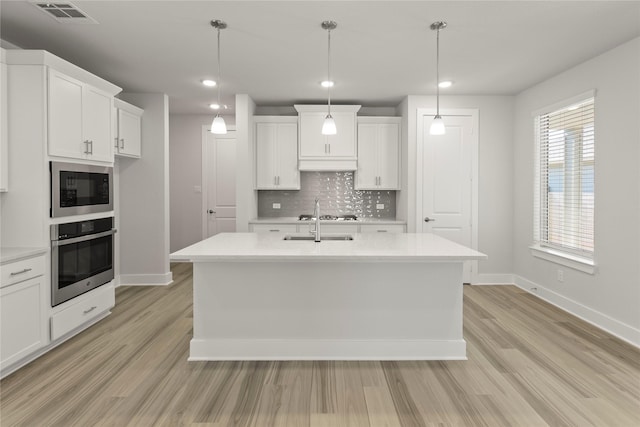 kitchen with oven, under cabinet range hood, built in microwave, visible vents, and decorative backsplash