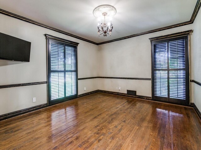 empty room with visible vents, ornamental molding, and wood finished floors