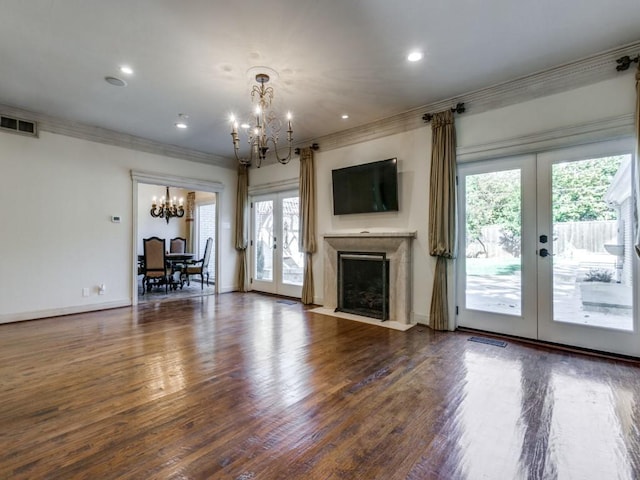 unfurnished living room with visible vents, dark wood finished floors, ornamental molding, french doors, and a chandelier