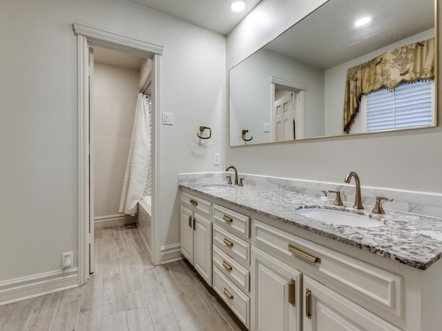 bathroom with double vanity, shower / tub combo, a sink, and wood finished floors