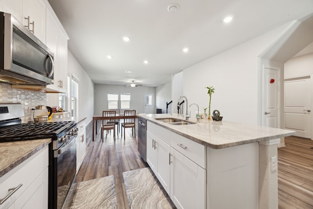 kitchen with tasteful backsplash, light wood-style flooring, stainless steel appliances, and a sink