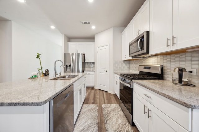 kitchen with tasteful backsplash, visible vents, an island with sink, appliances with stainless steel finishes, and a sink